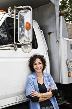 Hispanic woman truck driver and company delivery truck. Stock Photos