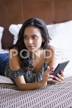 Hispanic Woman Using Digital Tablet On Bed