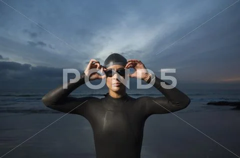 Hispanic woman in wetsuit on beach Stock Photos
