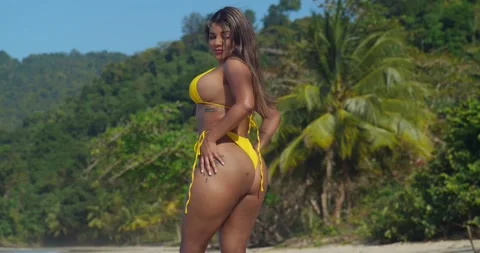 Hispanic woman in a yellow string bikini enjoys a sunny day on the beach Stock Footage 245689679