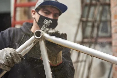 Hispanic worker removing the paint of a bicycle frame at his workshop Stock Photos