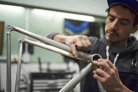 Hispanic worker sanding a bicycle frame at his workshop Stock Photos