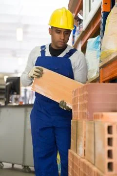 Hispanic worker stacking bricks in warehouse of building materials Foto stock