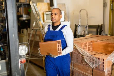 Hispanic worker stacking bricks in warehouse of building materials 写真素材