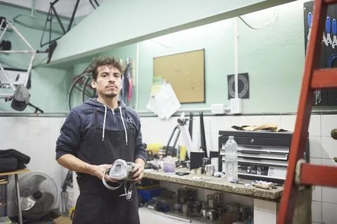 Hispanic worker standing in his workshop holding a protective respirator mask Stock Photos
