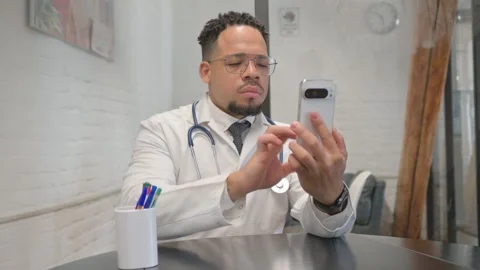 Hispanic Young Doctor Typing Message on Phone Video stock 305737258