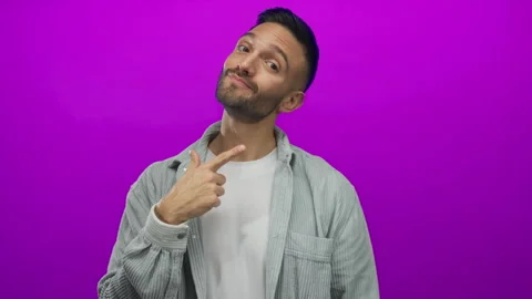 Hispanic young man with a confident expression points at himself against a .. Stock Footage 313909145