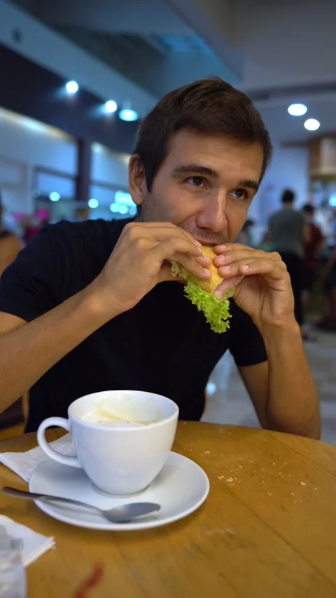 Hispanic young man eats a sandwich in a bar and says ok with his hand Stock Footage 163367266