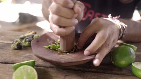 An Hispanic young man is preparing a chile and lemon spicy sauce with a mortar Stock Footage 221786241