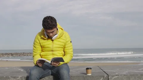 Hispanic young man reading a book outdoors Stock Footage 222570012