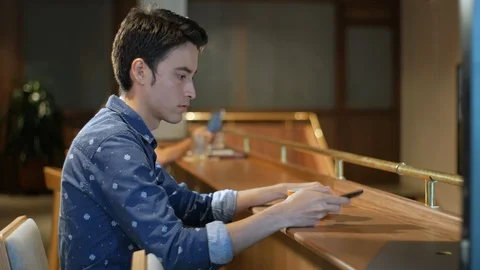 Hispanic young man sitting in coffee shop using smart phone and drinking coffee Vídeo Stock 101687869