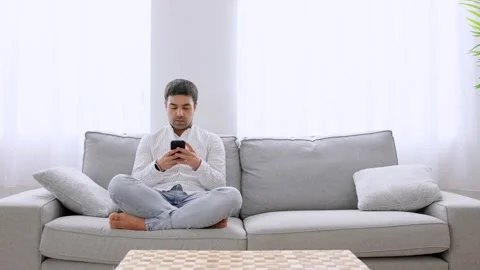 Hispanic young man using phone on sofa Stock Footage 264188165
