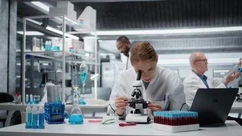 Histology technician using compound microscope for detailed cellular analysis 库存影片 325682444