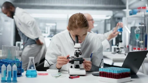 Histology technician using compound microscope for detailed cellular analysis Stock Footage 325748547