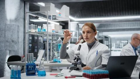 Histology technician using compound microscope for detailed cellular analysis Stock Photos