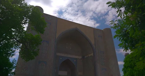 Historic arched madrasah facade framed by green trees in Samarkand Stock Footage 340333413
