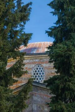 Historic brick building with circular window and copper dome framed by tall.. Stock Photos