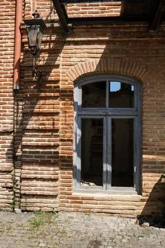 Historic brick building facade with arched window, ornate wall lantern Stock Photos