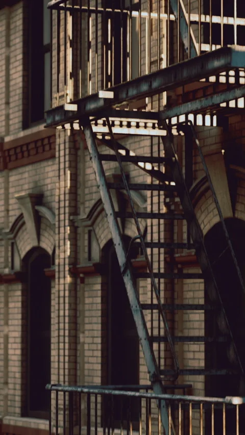 Historic brick building with fire escape in urban setting during golden hour Stock Footage 325075695