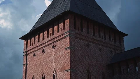 A historic brick tower stands prominently under an overcast sky. The video Vídeo Stock 344527993