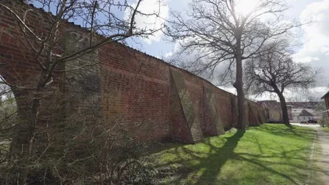 Historic brick town wall framed by trees and lawn Stock Footage 340292828