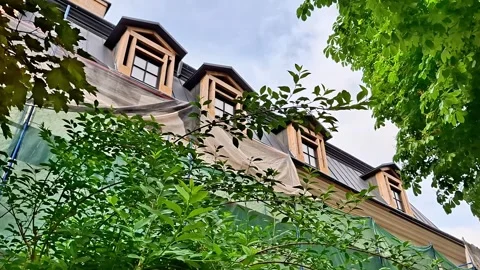 Historic Building with Dormer Windows Framed by Lush Green Trees Stock Footage 337923738