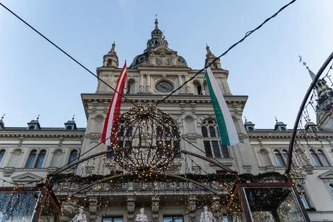 Historic building facade with clock tower, flags and decorative lights Stock Photos
