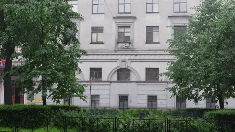 Historic building facade framed by lush green trees, symmetrical architecture Stockbeeldmateriaal 339489043