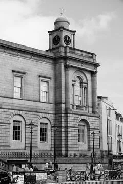Historic clock tower and stone facade with pedestrians on city street view Stock Photos