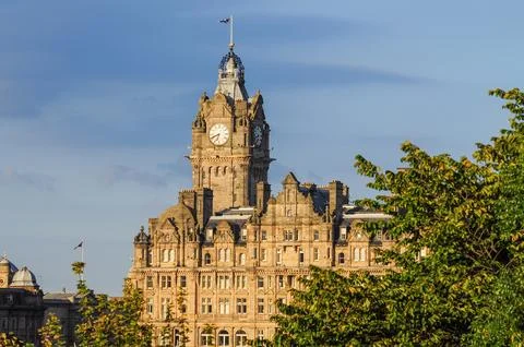 Historic clock tower with clear sky and lush trees in foreground Stock Photos