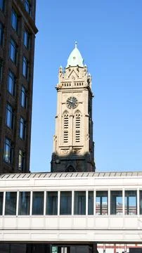 Historic clock tower framed by modern buildings against blue sky Fotos de archivo