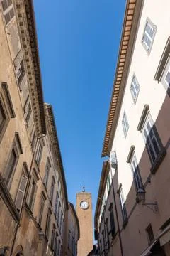 Historic Clock Tower Framed by Old Town Buildings and Clear Blue Sky, Orvie.. Stock Photos
