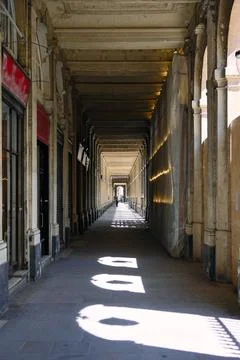 Historic colonnade with sunlight patterns and deep perspective in old city Foto stock