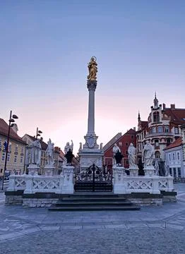 Historic Column Surrounded by Statues in a Quaint European Town During Twilight Foto stock