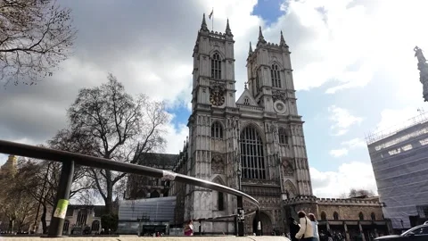 Historic Gothic Westminster Abbey facade framed by a curved railing, tourists Stock Footage 332254742