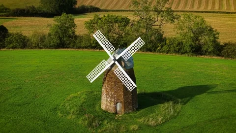 Historic grain windmill for wheat flour production on green meadow. Old stone Stock Footage 346812309