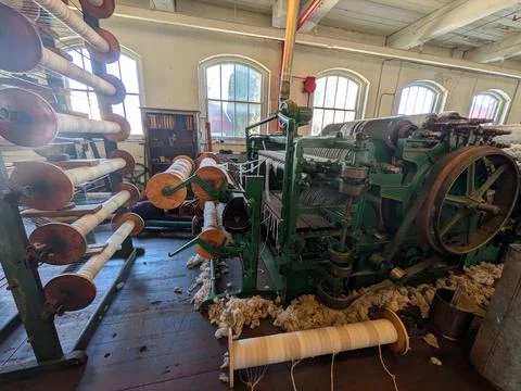 Historic green textile machine surrounded by raw sheep wool 写真素材
