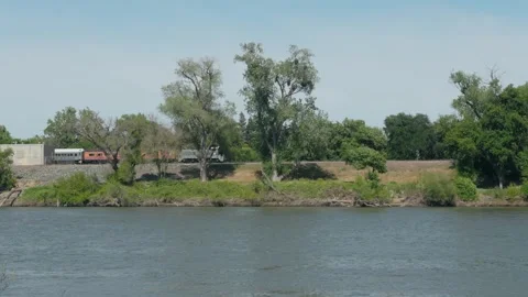 A historic museum train rides along the scenic riverbank Stock Footage 345742541