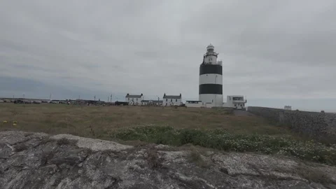 Historic navigational lighthouse structure on grassy headland in ireland Stock Footage 340465760