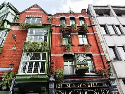 Historic O'Neills pub facade with clock on red brick building in Dublin, Ir.. Stock Photos