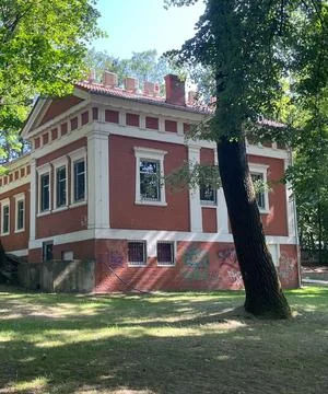 Historic Red Brick Classical Building with White Columns and Chimneys in Park Stock Photos