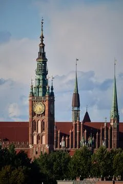 Historic red brick clock tower rising above green treetops in Gdansk, Poland 스톡 사진