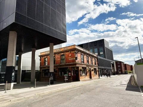 Historic red brick pub beneath a modern cantilevered building on a Manchest.. Stock Photos