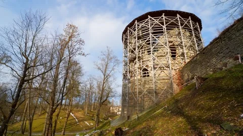 Historic round tower wrapped in structural scaffolding on a sunlit hillside Stock Footage 333033157