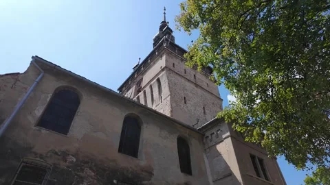 Historic Sighisoara Clock Tower and old architecture framed by trees in Stock Footage 346520433