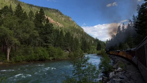 Historic steam engine train follows beautiful Colorado mountain river scene Stock Footage 113876448