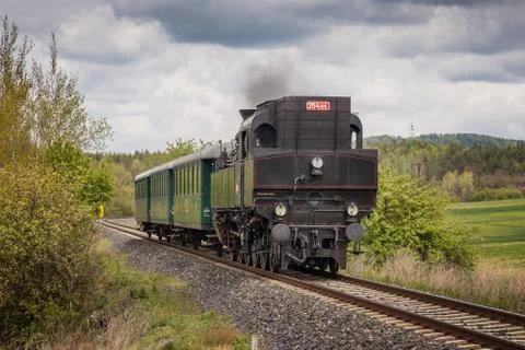 A historic steam train driving into a bend through a field Stock Photos