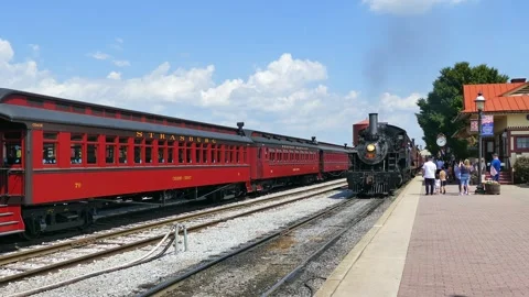 A historic steam train pulls into a busy station. People gather on platform Stock Footage 338059041