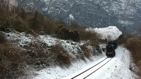 Historic steam train rolling through the snowy valley in a winter day Stock Footage 121429264