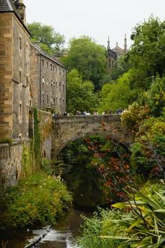 Historic stone bridge over leafy ravine beside old Edinburgh buildings Stock Photos